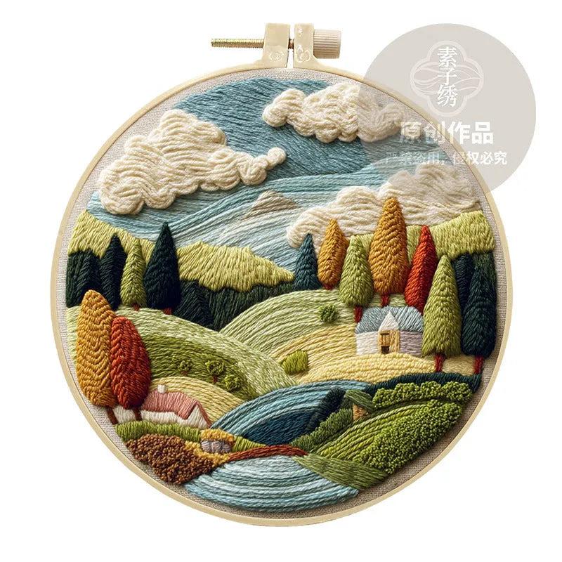 DIY embroidery kit with landscape-printed cotton fabric, embroidery hoop, needles, and coloured thread spools.