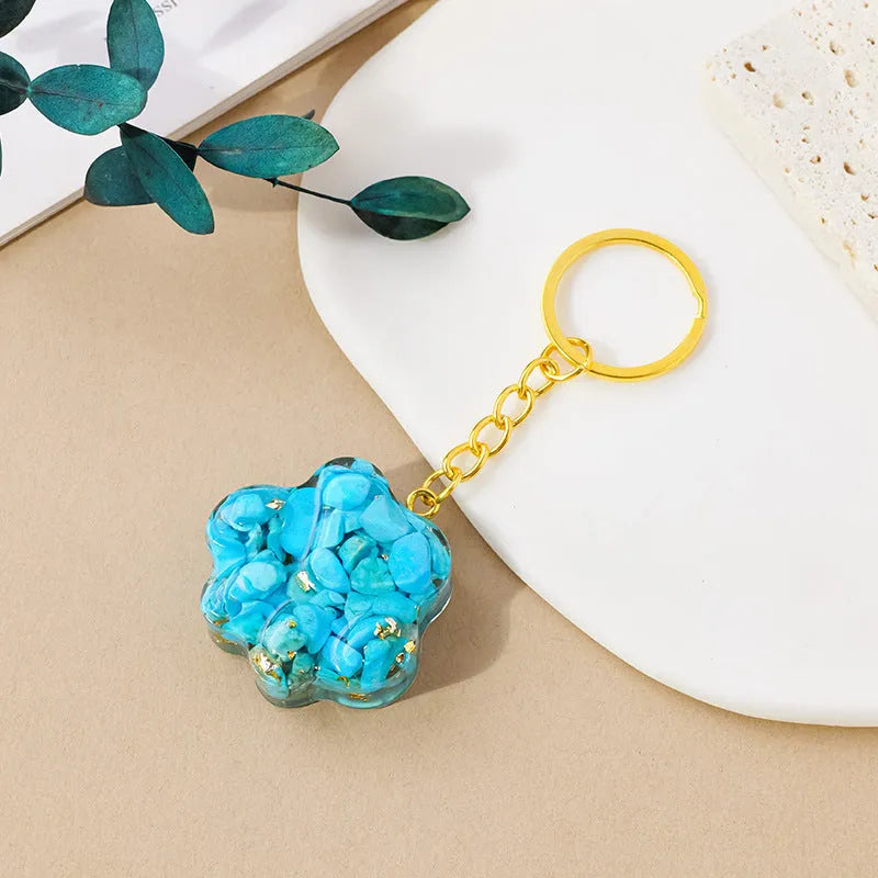 Natural crystal cat's paw shaped keychain charm on a keyring, showing colour variations of different gemstones.