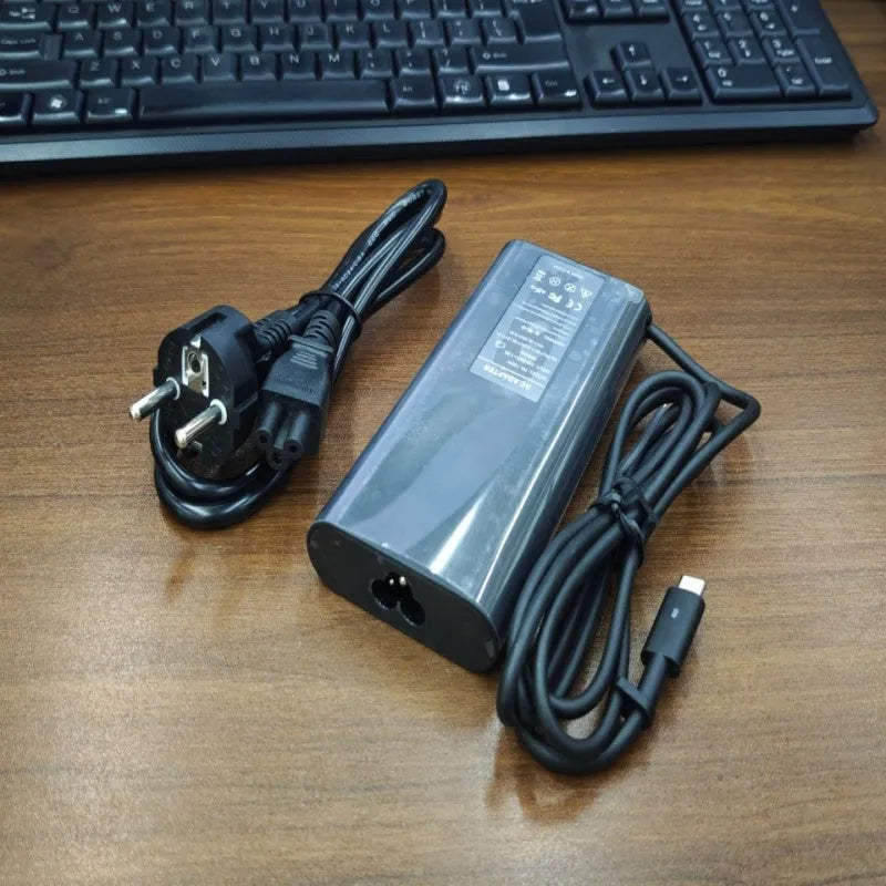 Black oval 65W USB-C laptop power adapter with Type-C port and multiple international power cords