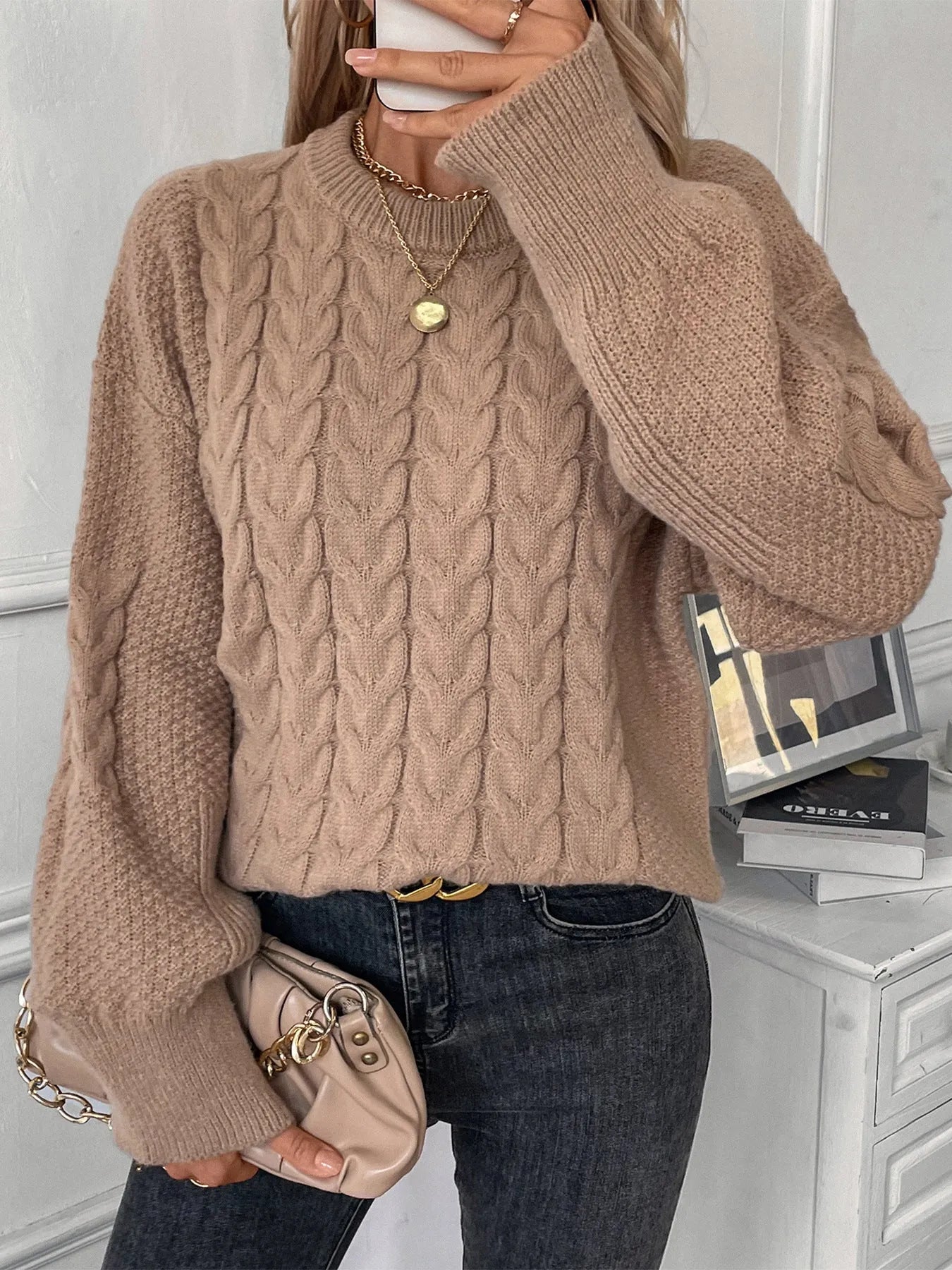 Women's loose beige casual sweater with round neck and twist detail on a hanger.