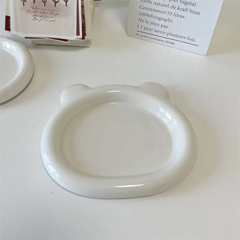 White round ceramic plate with bear doodle design, used as a saucer for a small succulent plant pot.