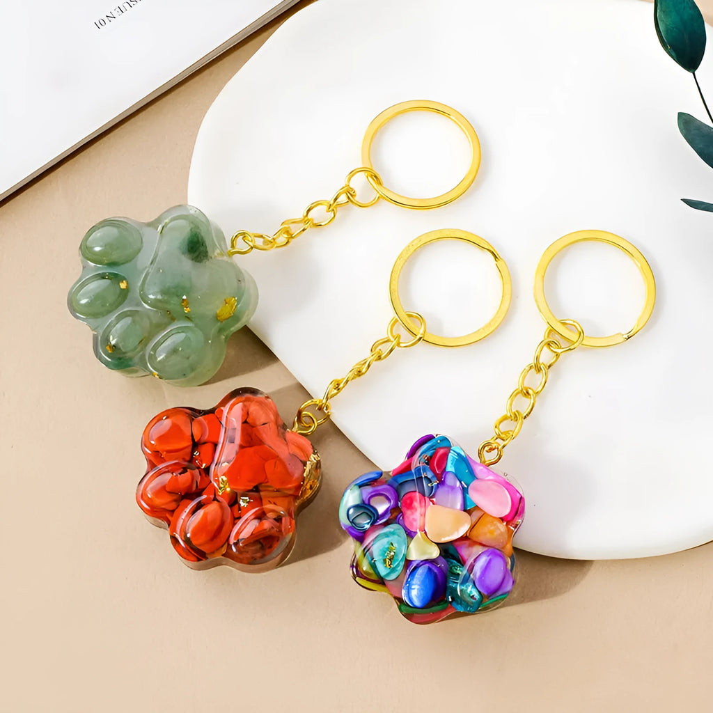 Natural crystal cat's paw shaped keychain charm on a keyring, showing colour variations of different gemstones.