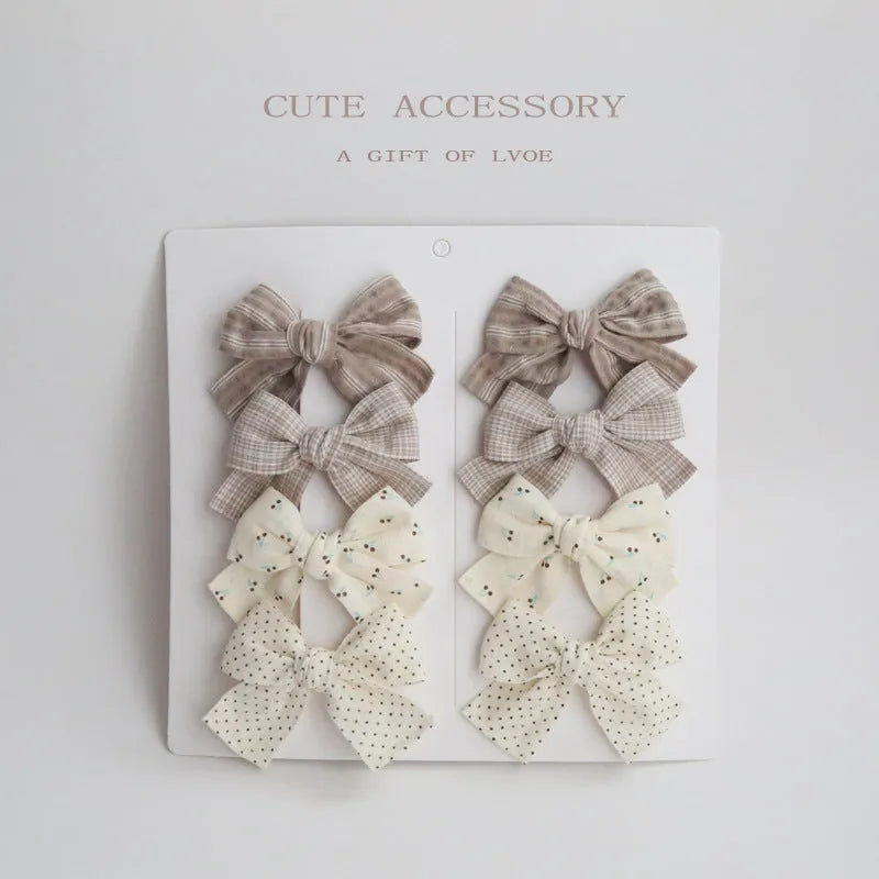 Set of eight fabric hairclips with dovetail bows in a chosen colour like beige grid dots or pink.
