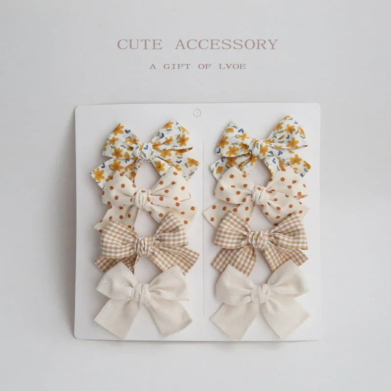 Set of eight fabric hairclips with dovetail bows in a chosen colour like beige grid dots or pink.