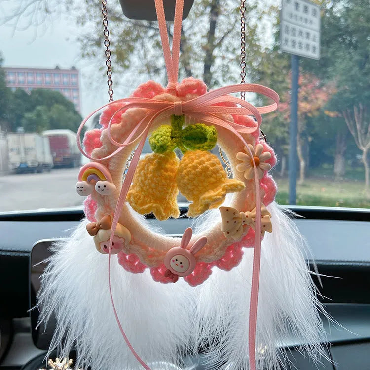 Handmade woven wool bell orchid car pendant on a green background, showing textured detail.