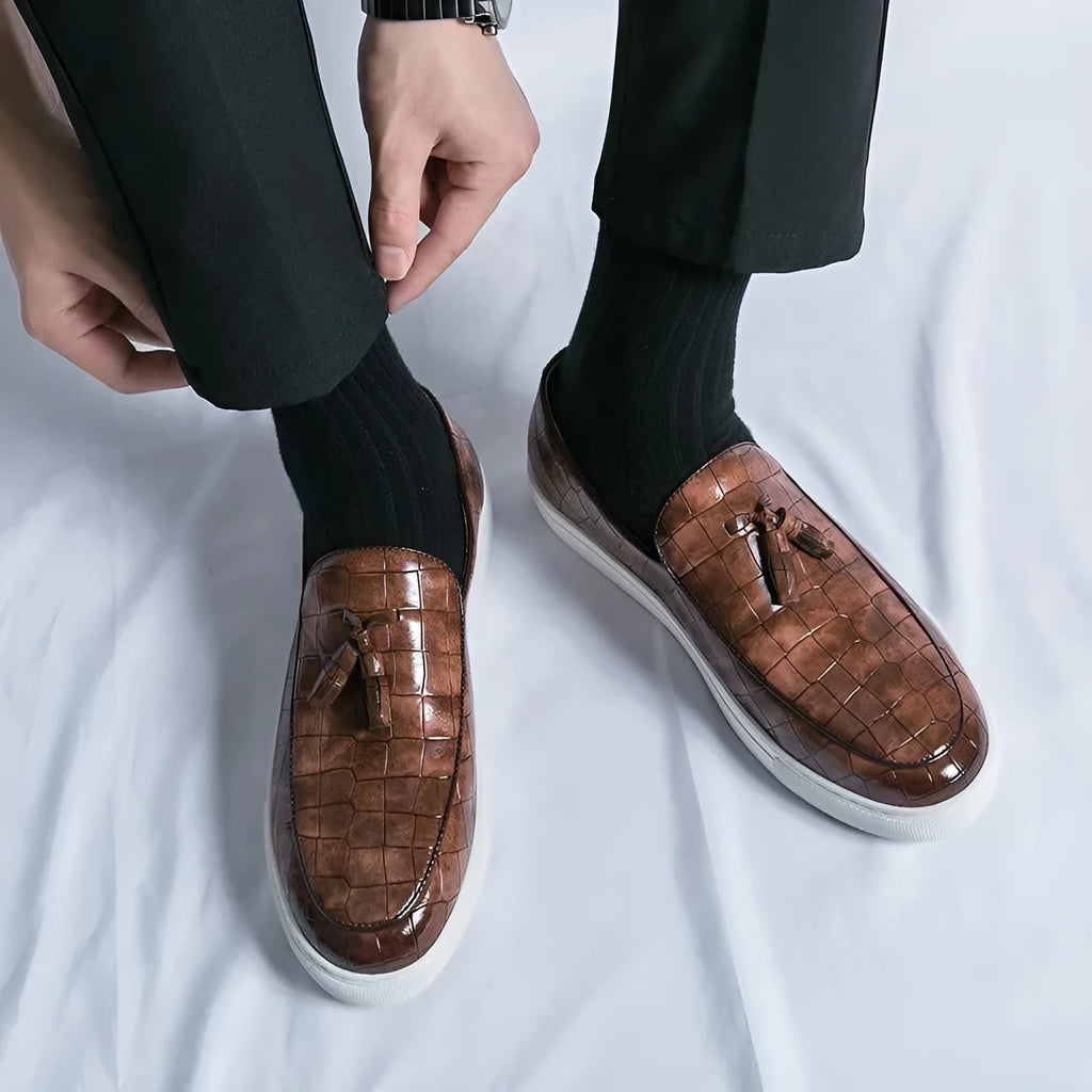 Men's black faux leather sneakers with a tassel detail on the upper, shown on a white background.