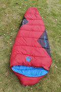 Outdoor cotton sleeping bag in army green, shown next to its grey compression storage sack