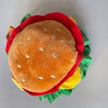 Cartoon-style burger headdress hat for cats, shown in soft fabric with adjustable strap.