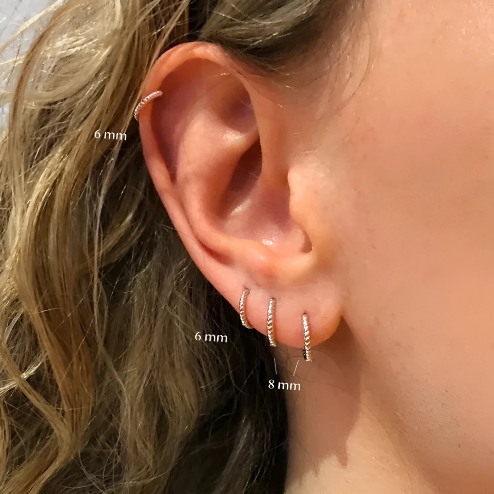 A pair of twisted sterling silver round earrings in a geometric design on a white background.