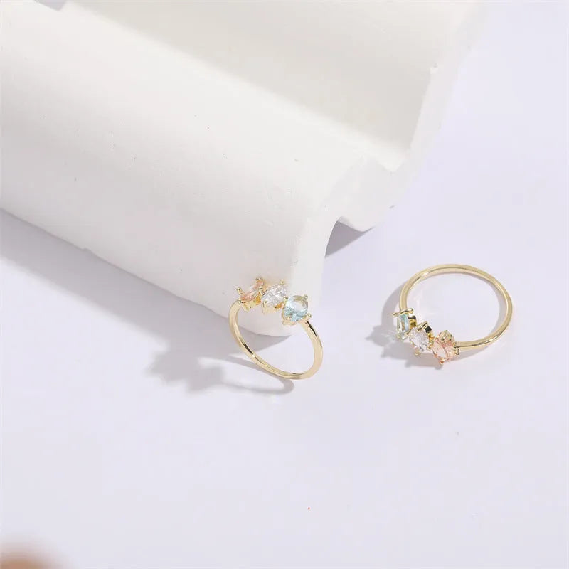 Gold geometric women's ring with horse eye design and three coloured zircon stones on a triangular band.