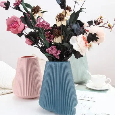 A simple style melamine plastic decorative flower vase in blue, measuring 16cm by 20cm, on a desktop.