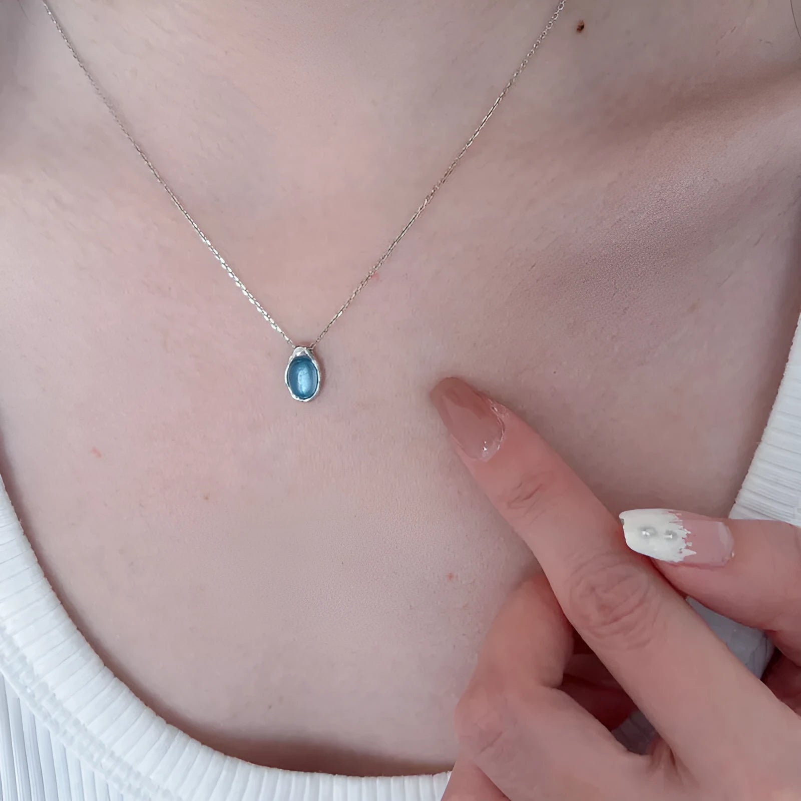Geometric navy blue water drop pendant necklace on a model, showing the adjustable cross chain.