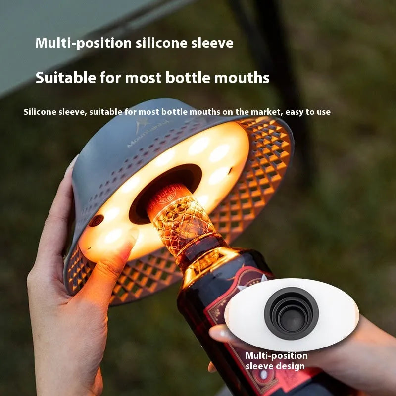Beige wine bottle shaped rechargeable camping lantern with LED light on a wooden surface.