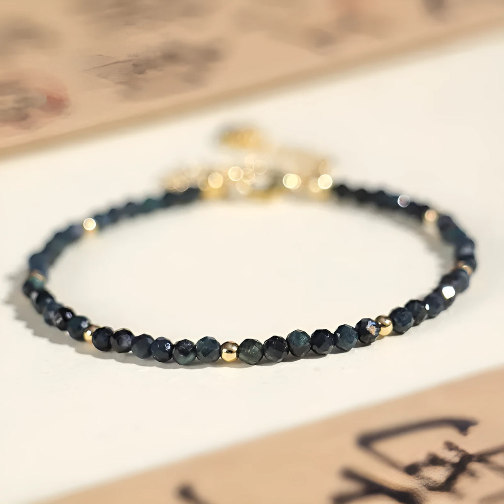 Close-up of a women's blue tourmaline bracelet with 3mm beads and gold spacer beads.