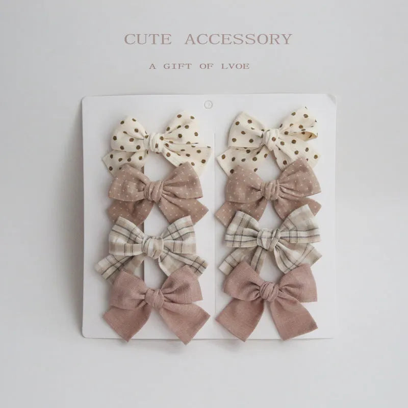 Set of eight fabric hairclips with dovetail bows in a chosen colour like beige grid dots or pink.