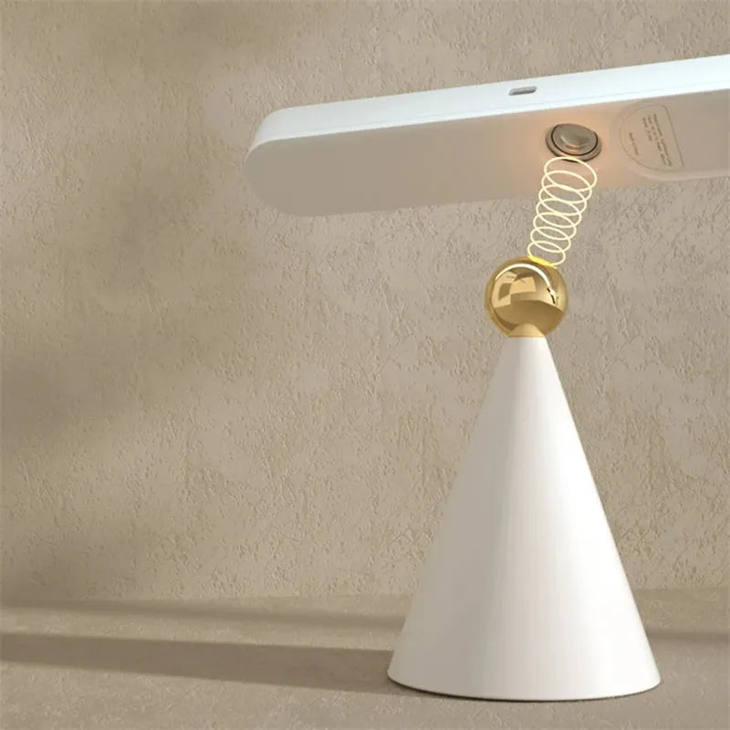 White geometric desk lamp with magnetic base and touch control on a wooden table.