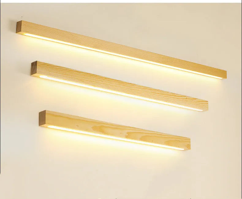 Walnut colour minimalist wooden and acrylic strip wall lamp in three length options on a white wall.