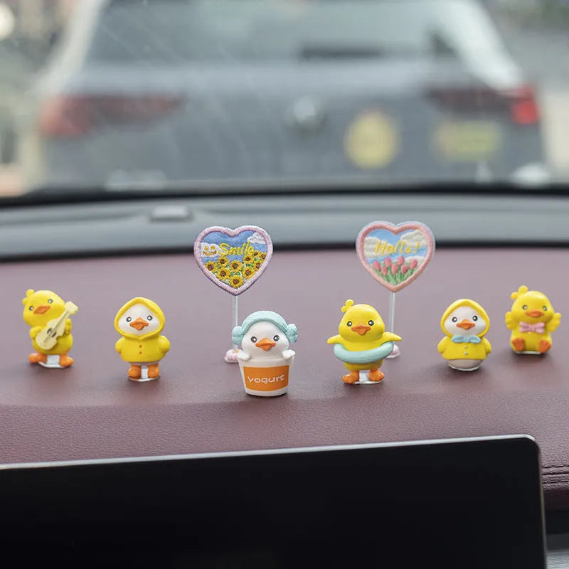 Set of six small cartoon duckling figures and one hello sign for car dashboard decoration.