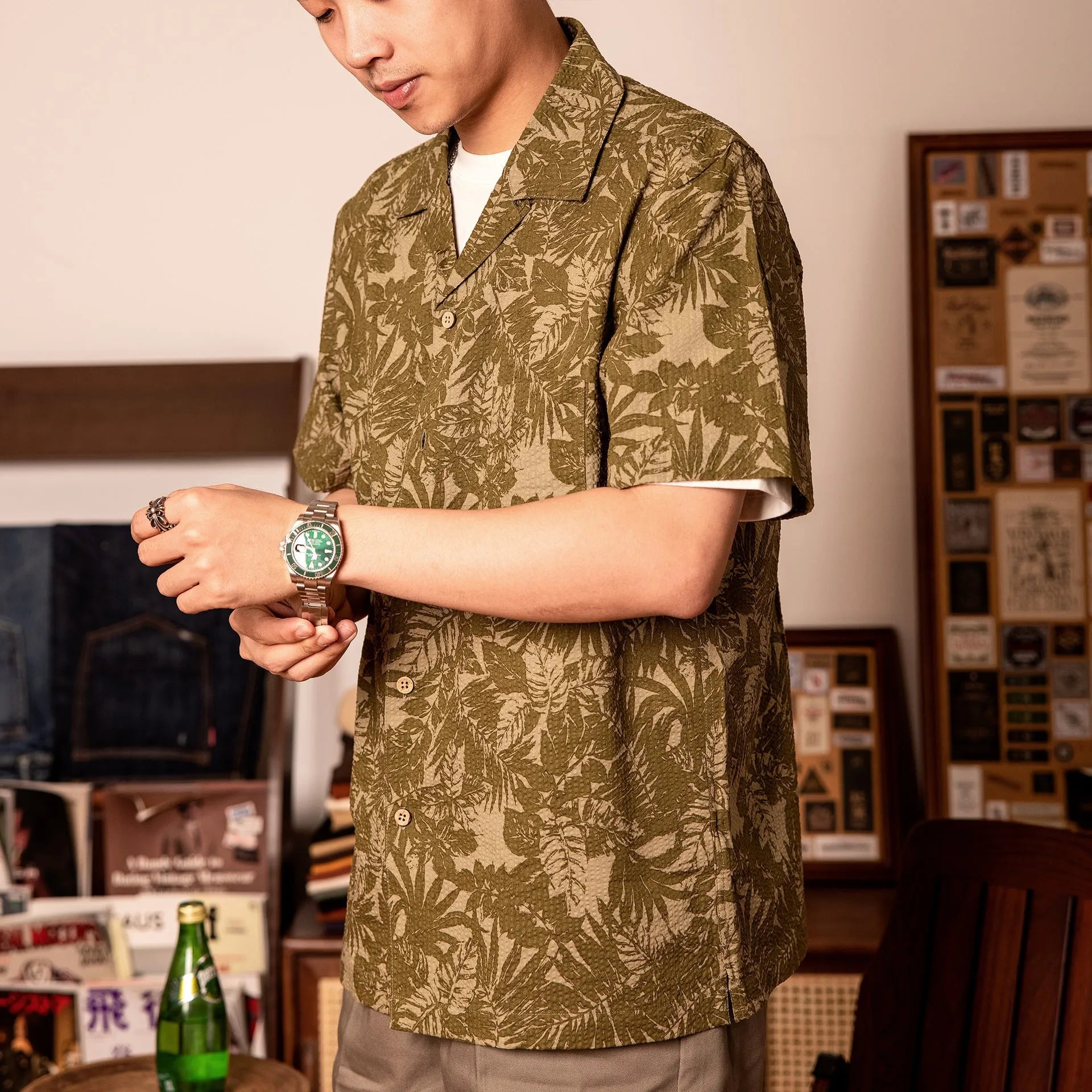 Man wearing a vintage floral print seersucker shirt with a Cuban collar in a green colour, showing loose fit.