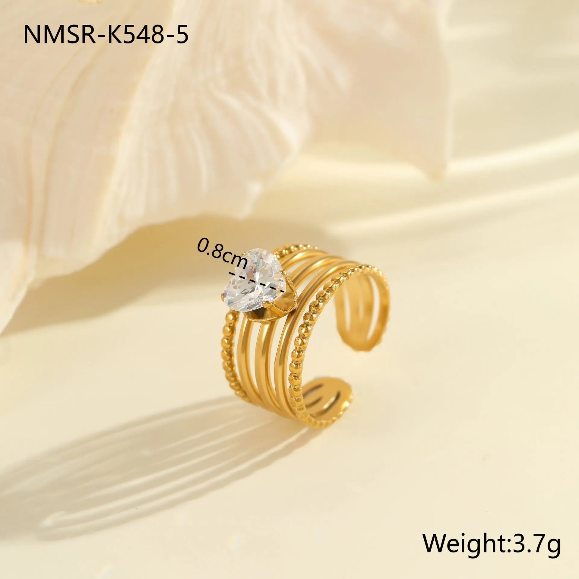 Gold inlaid zircon geometric heart and drop shape stainless steel ring on white background.