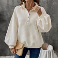 Women's beige textured polo collar long sleeve sweater laid flat.