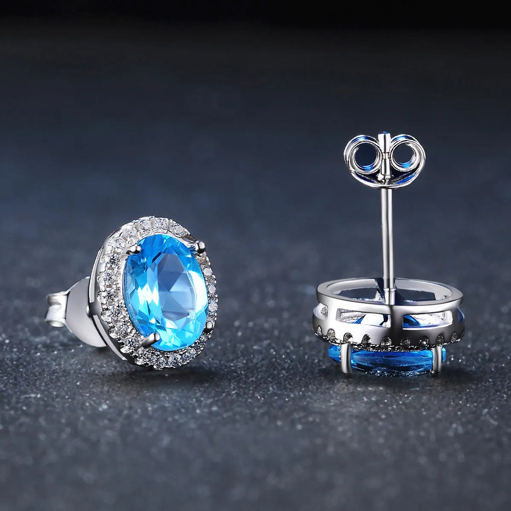 Women's sterling silver jewellery set with blue topaz gemstones in geometric design including earrings, ring, pendant, and necklace