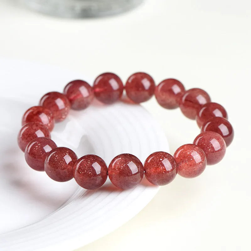 Natural strawberry quartz bracelet with geometric red crystal beads on a white background