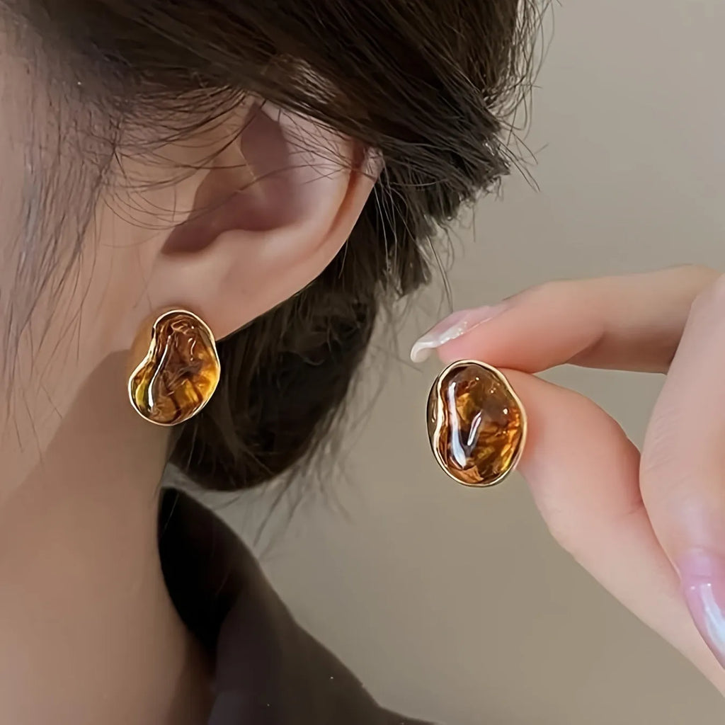 Handmade geometric earring set showing three styles: round piece, irregular amber, and water drop tigereye studs with tassels.