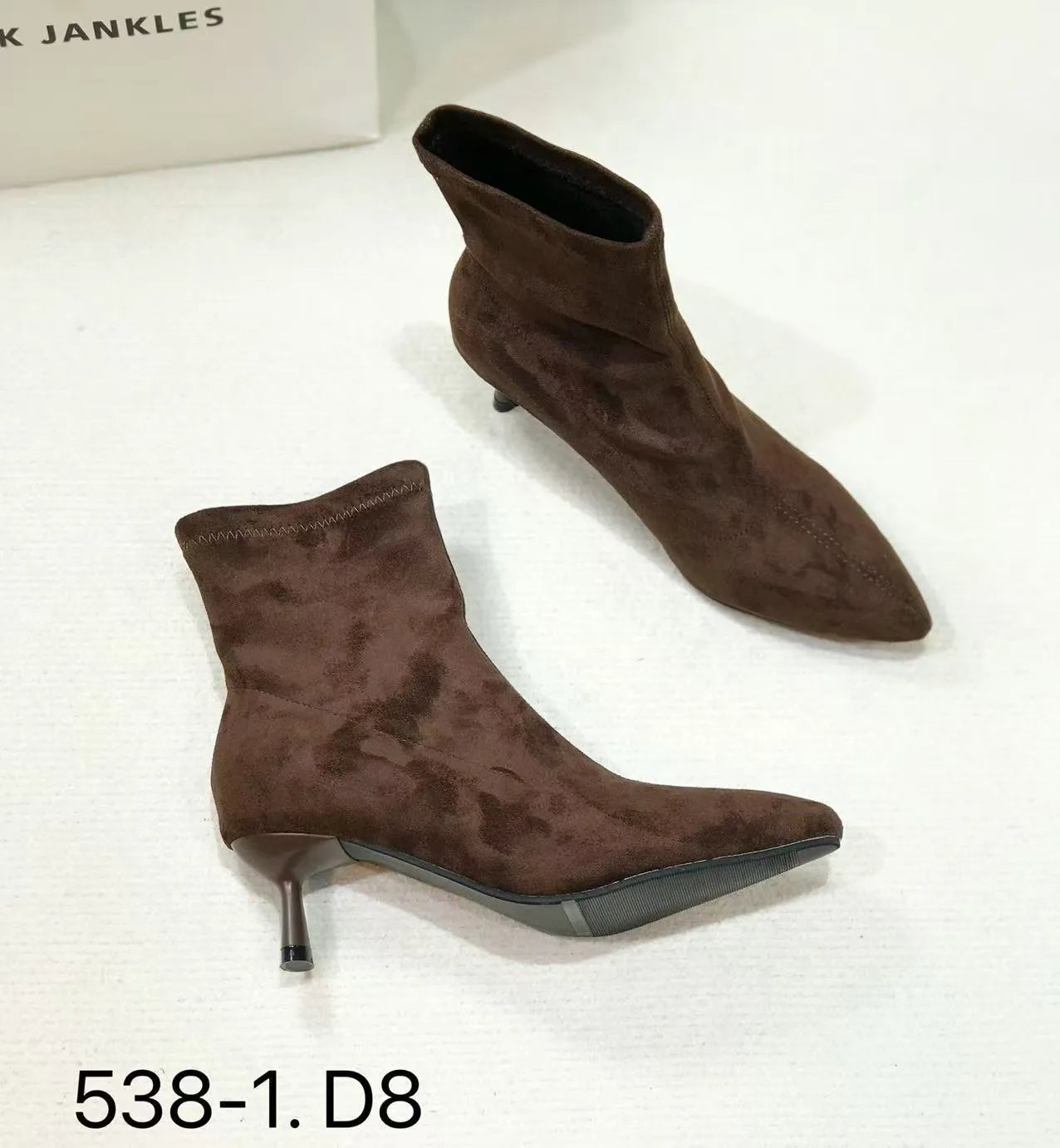 Black pointed toe stiletto ankle boots with a mid-calf sock length on a model.