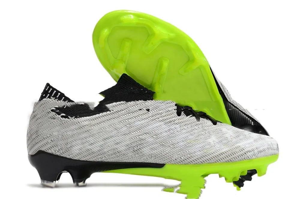 Men's low-top knitted football shoes with white/blue colourway, showing FG studs on rubber outsole and lace-up front.