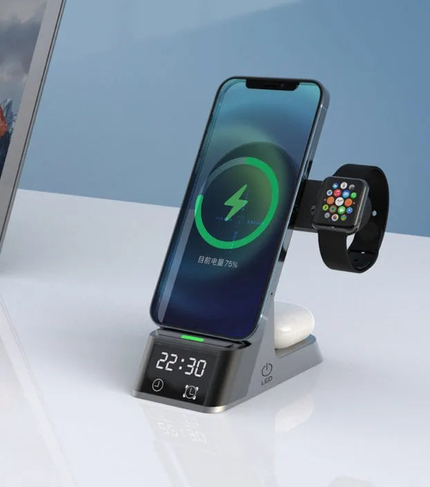 Black six-in-one wireless charging alarm clock station on a desk next to a phone and smartwatch.