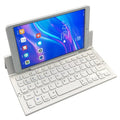 A black mini folding wireless Bluetooth keyboard shown open next to a tablet.