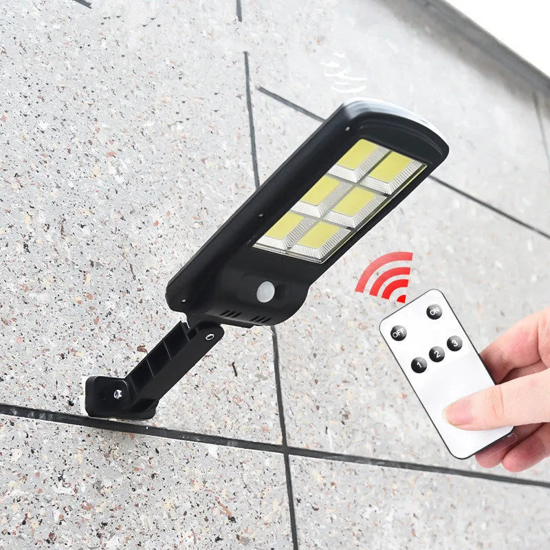 Black outdoor solar-powered motion sensor security light mounted on a wall.
