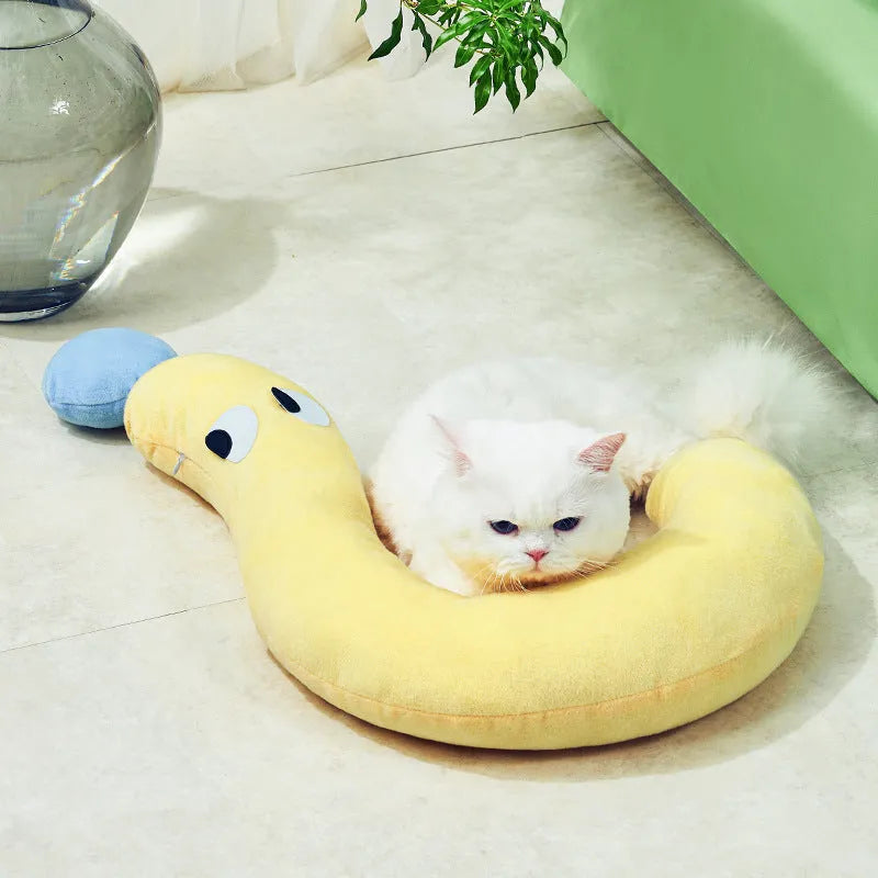 A rectangular blue pet sleeping pillow on a floor, shown next to a small dog for scale.
