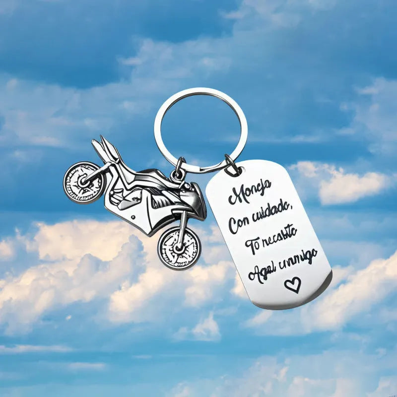 Polished stainless steel motorcycle key ring with inspirational charm on a flannel bag.