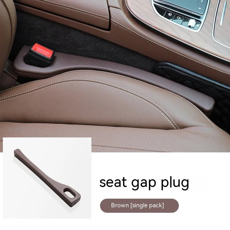 A flexible polyurethane car seat gap filler strip in black, placed between a car seat and centre console.