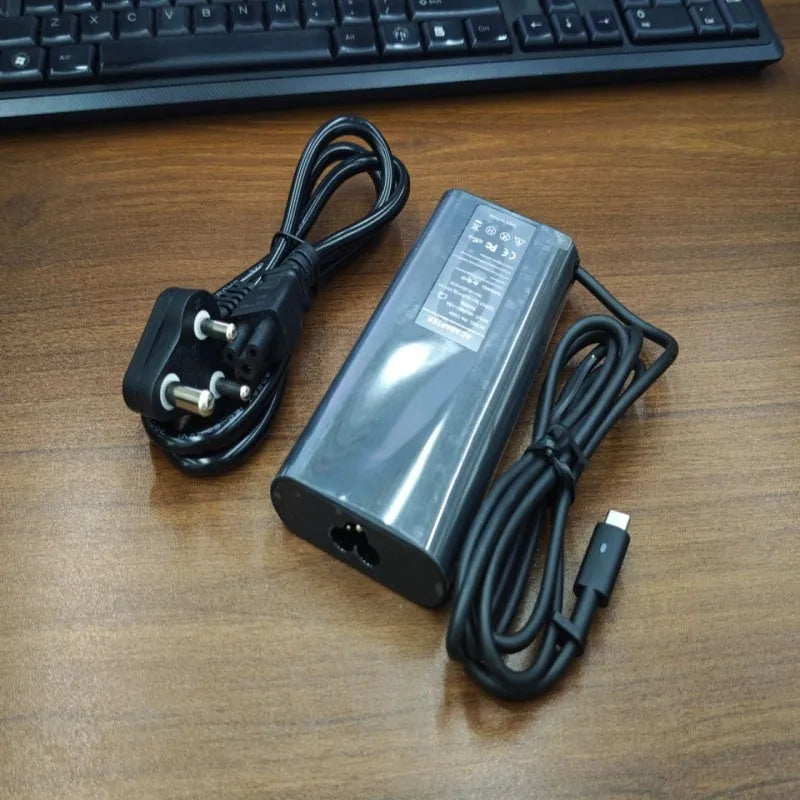 Black oval 65W USB-C laptop power adapter with Type-C port and multiple international power cords