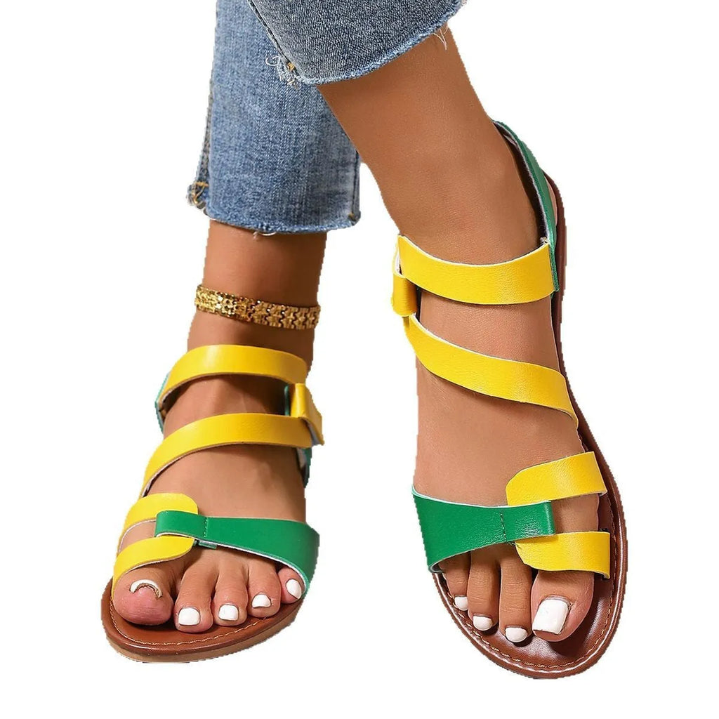 Women's flat sandals with Velcro strap on a round toe, shown in black, brown, and multi-colour options.