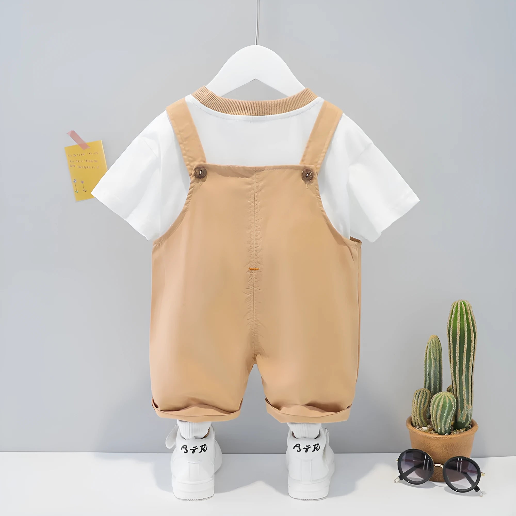 A yellow cotton baby overalls with a cartoon print, featuring short sleeves and openable straps.