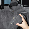 Men's loose grey linen cardigan shirt with a stand collar on a hanger.