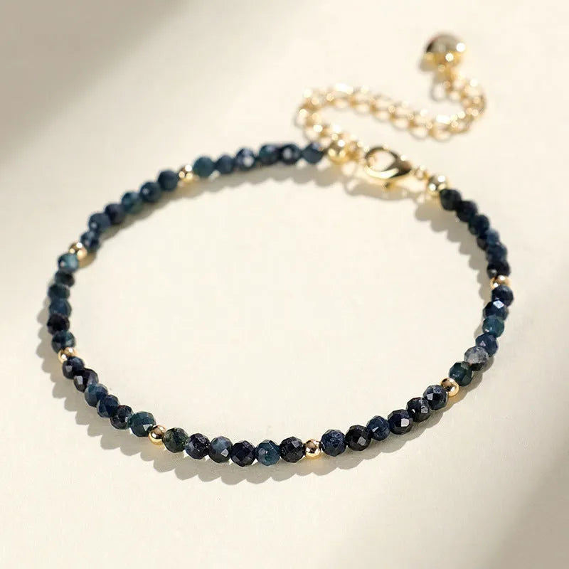 Close-up of a women's blue tourmaline bracelet with 3mm beads and gold spacer beads.