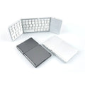 A closed black tri-fold Bluetooth keyboard next to a smartphone, showing its slim 0.8cm profile.