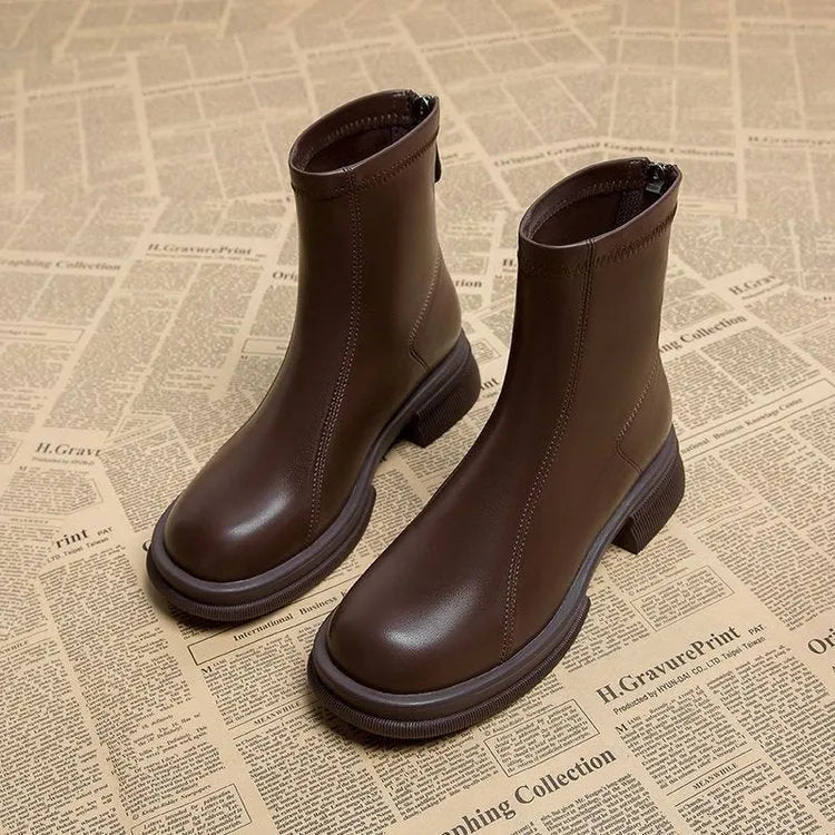 Women's black flat-heel ankle boot with back zipper and round toe on a neutral background.