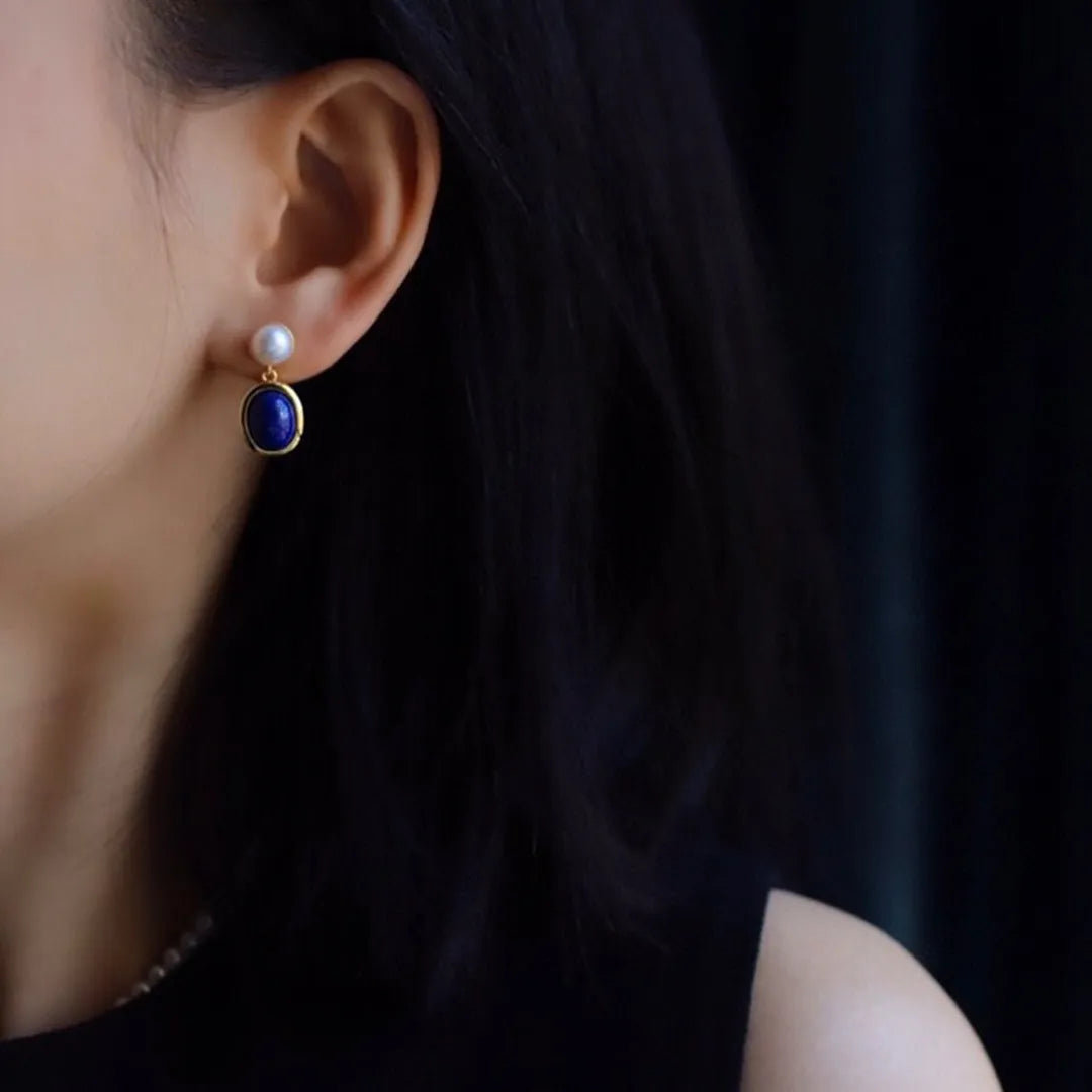 A pair of simple silver earrings with blue lapis lazuli pearls and auspicious patterns.
