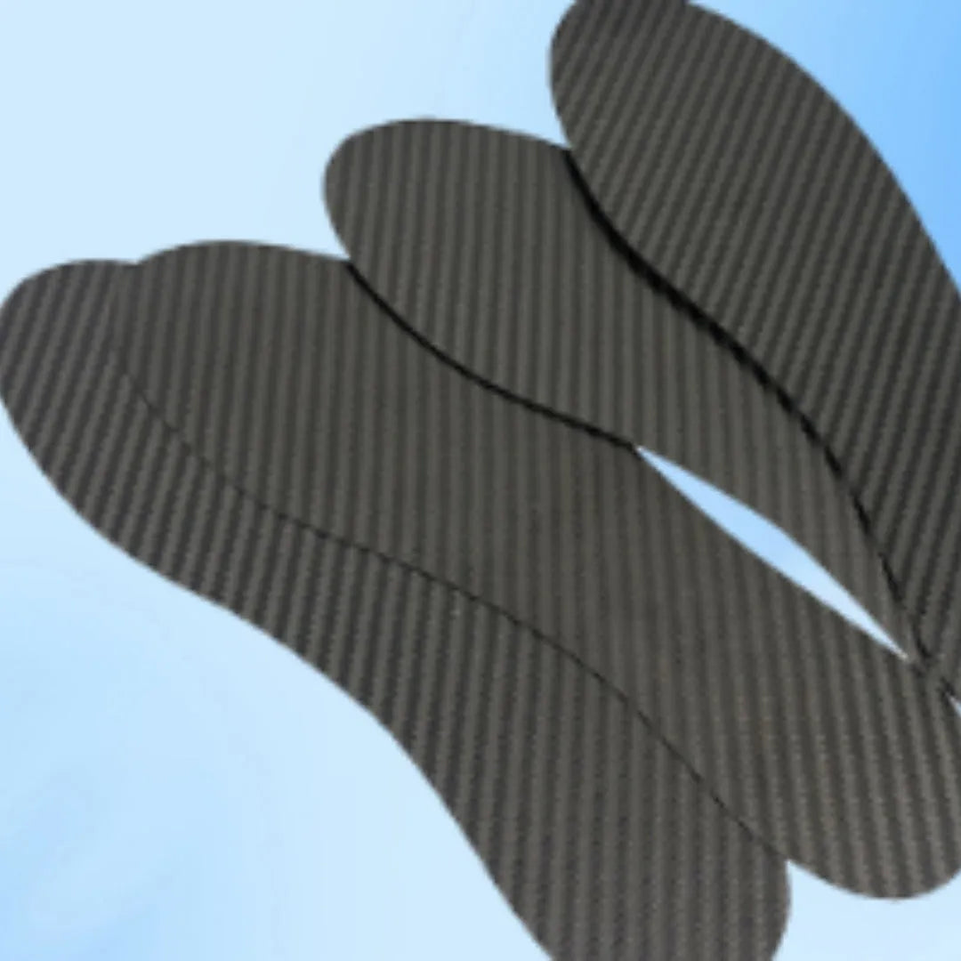 A pair of thin, black 3K carbon fibre running insoles showing the textured weave pattern, placed next to a running shoe.
