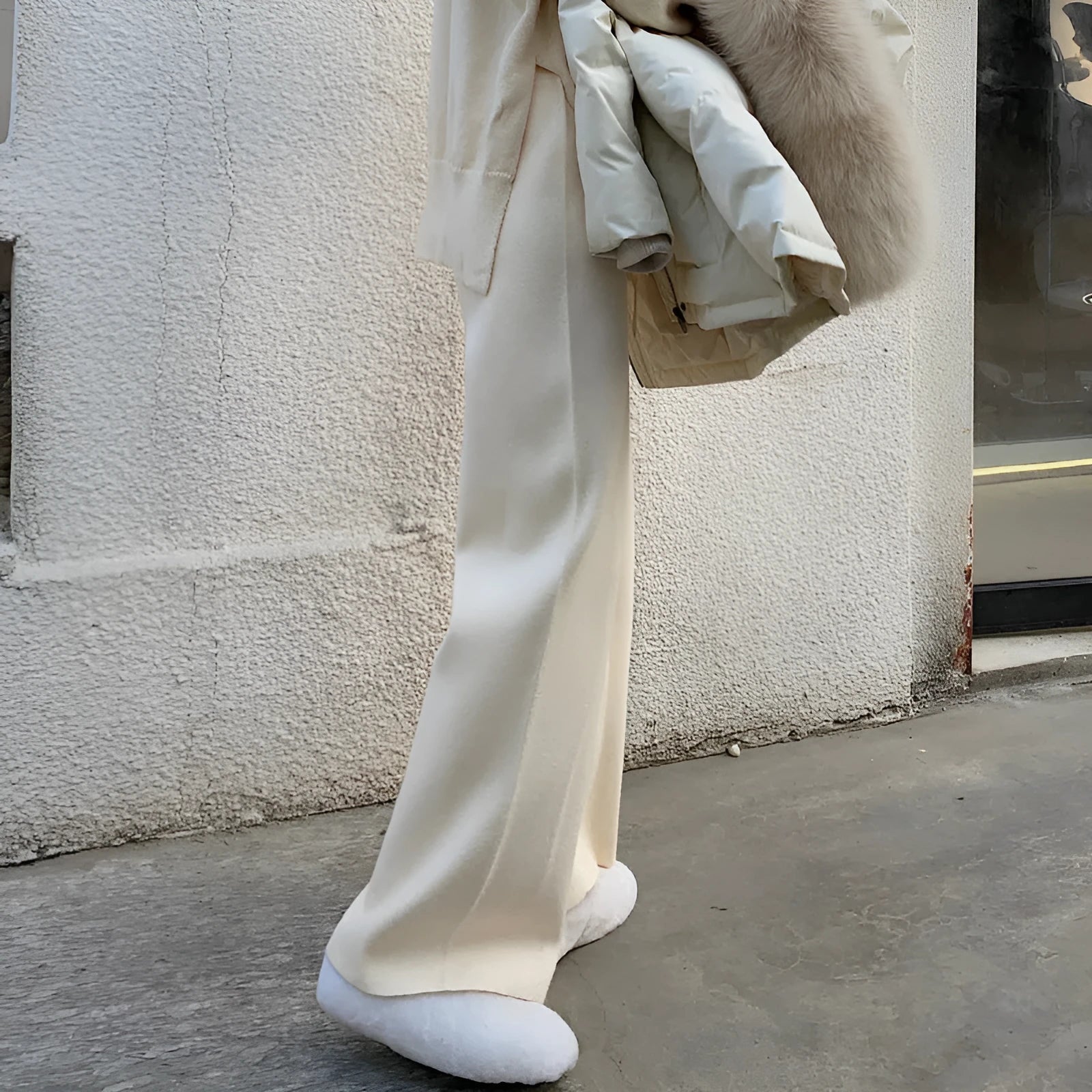 Women's cream white thick knitted wide-leg trousers with a high waist and drooping hem laid flat.