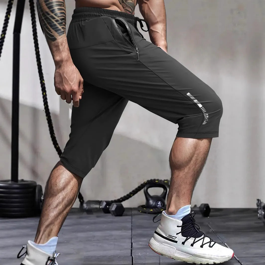 Man wearing grey cropped nylon sports pants with straight leg for summer beach activity