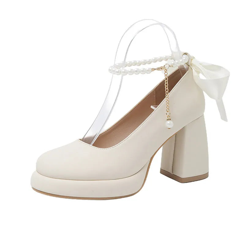 Women's beige Mary Jane shoes with a chunky heel and an ankle-strap buckle on a round toe.