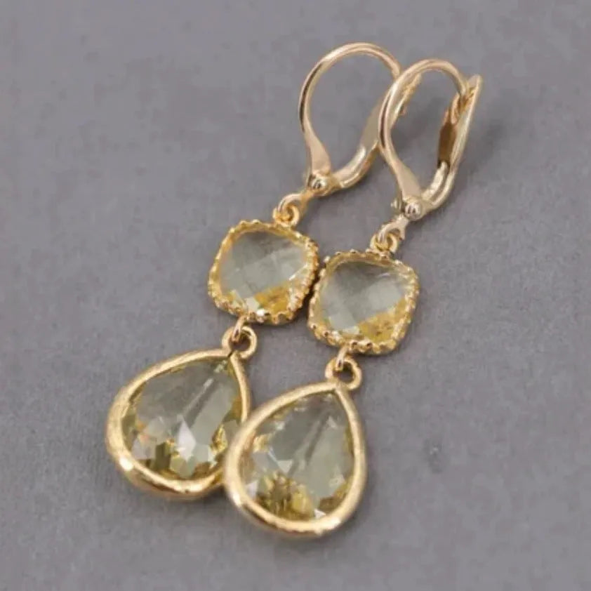 Gold geometric long fringe drop earrings with water droplet design on a white background.