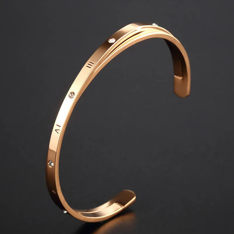 Open-ended stainless steel ladies bracelet with a love symbol and zircon detail, shown in rose gold finish.